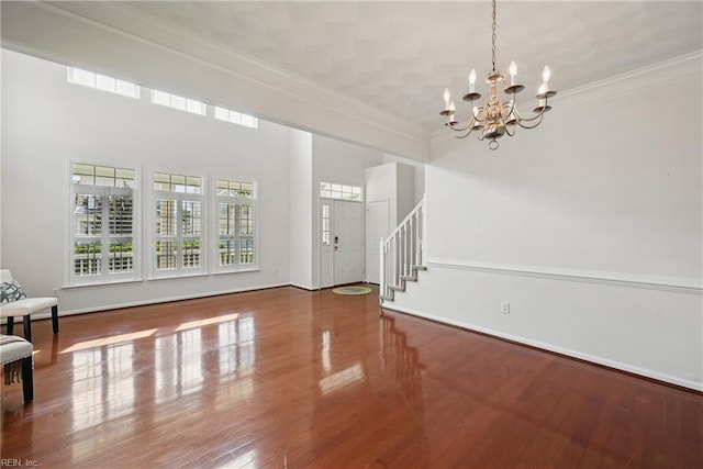 2043 Queens Point Dr, Suffolk, VA 23434 - unfurnished living room featuring a chandelier, ornamental molding, stairs, wood finished floors, and a high ceiling