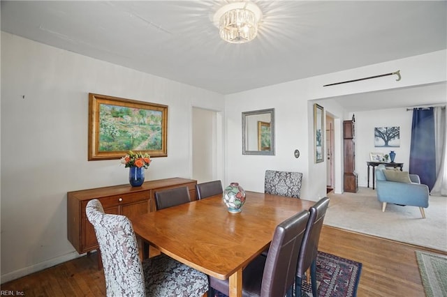 dining area with dark wood-type flooring and a chandelier
