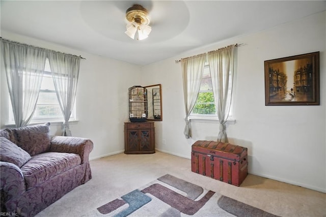 carpeted living room featuring ceiling fan and baseboards