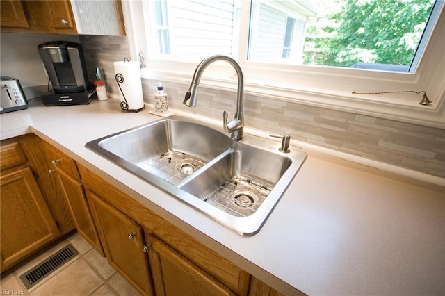 2933 Crossings Dr, Chesapeake, VA 23321 - kitchen view of a sink, brown cabinets, and tasteful backsplash