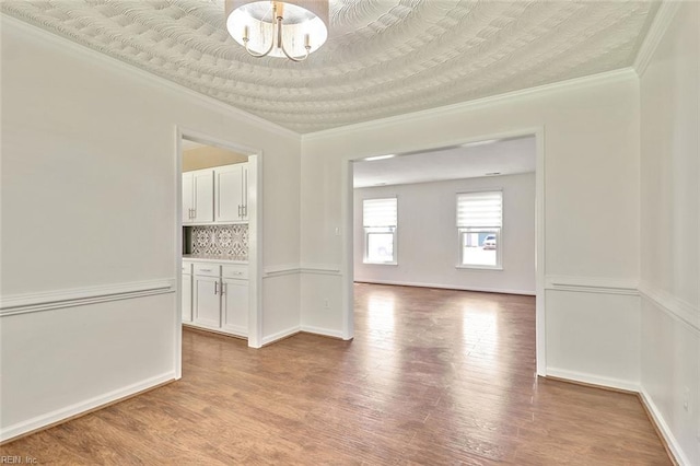 unfurnished room featuring light wood-style floors, ornamental molding, and baseboards