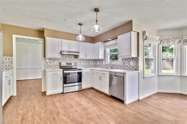 kitchen with appliances with stainless steel finishes, under cabinet range hood, light countertops, light wood-style flooring, and tasteful backsplash