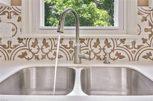kitchen view of a sink, decorative backsplash, and light countertops