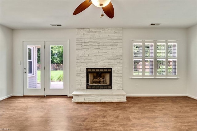 unfurnished living room with a ceiling fan, a fireplace, wood finished floors, and baseboards