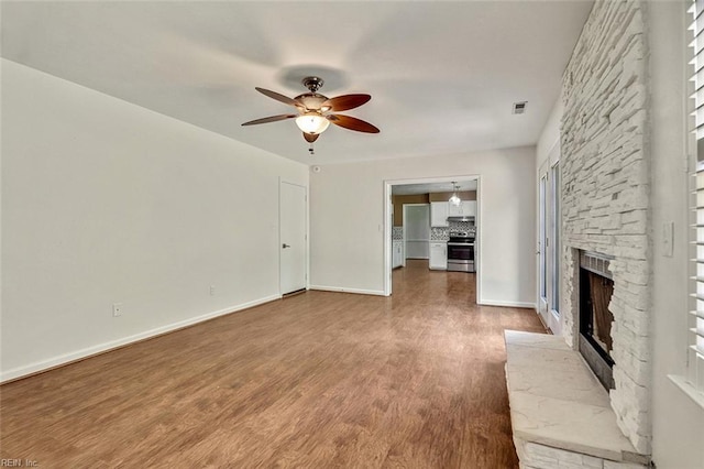 unfurnished living room with a ceiling fan, a fireplace, wood finished floors, and baseboards