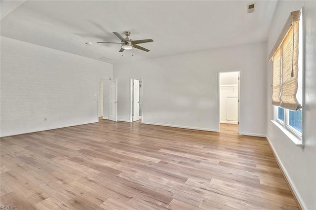 spare room featuring a ceiling fan, light wood-type flooring, and baseboards