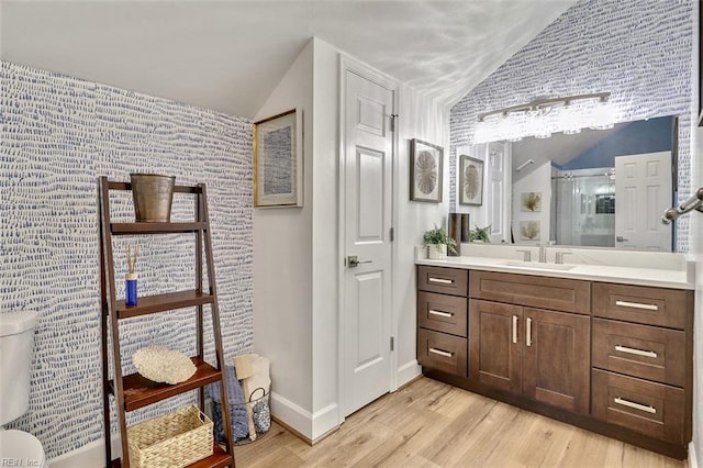full bathroom featuring lofted ceiling, a shower stall, wood finished floors, vanity, and baseboards