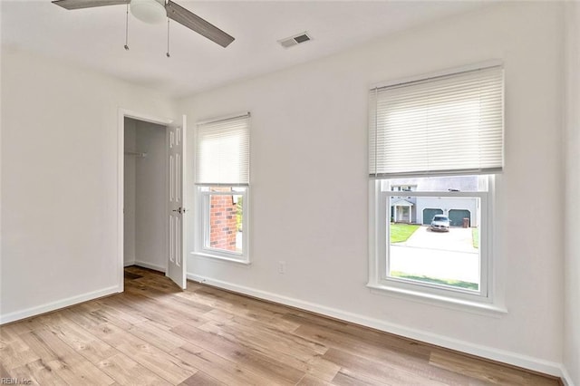 unfurnished room with light wood-type flooring, a ceiling fan, and baseboards