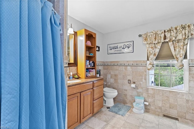 150 Ridge Rd, Poquoson, VA 23662 - full bathroom featuring toilet, tile walls, vanity, wainscoting, and tile patterned floors