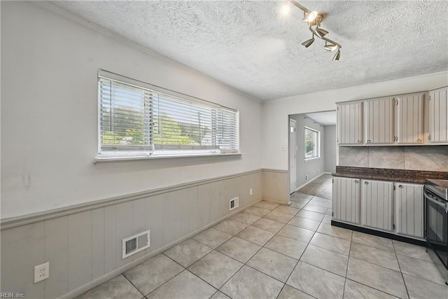 3813 Honeytree Ln, Virginia Beach, VA 23452 - kitchen with range, wainscoting, light tile patterned flooring, dark countertops, and a textured ceiling