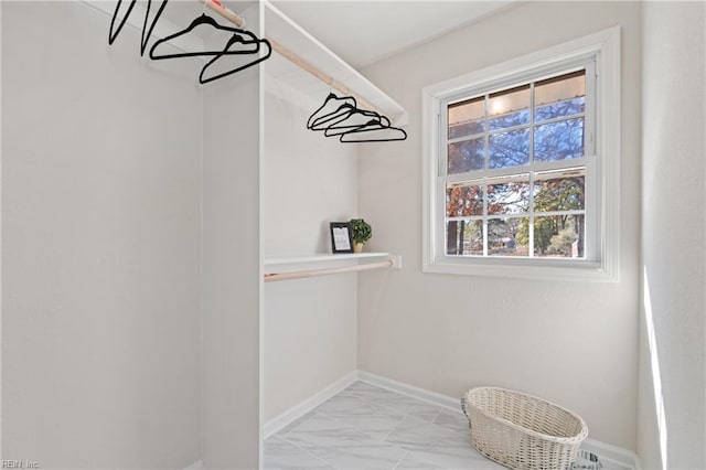 walk in closet with light marble finish flooring