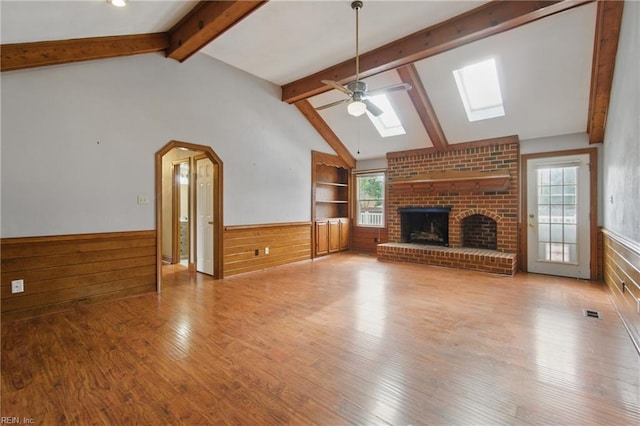 1121 Vineyard Dr, Chesapeake, VA 23322 - unfurnished living room with a skylight, a wainscoted wall, a fireplace, wood finished floors, and ceiling fan