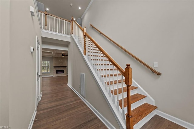 staircase with wood finished floors, baseboards, a fireplace, recessed lighting, and a ceiling fan