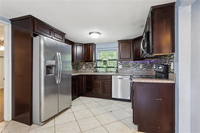 kitchen featuring stainless steel appliances, backsplash, dark brown cabinetry, a sink, and light tile patterned floors