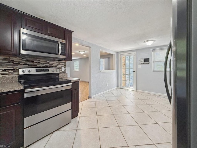 kitchen with appliances with stainless steel finishes, a textured ceiling, baseboards, dark brown cabinets, and light tile patterned floors
