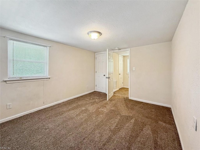 empty room featuring carpet floors, a textured ceiling, and baseboards