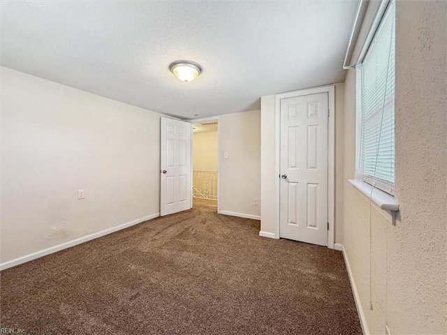 unfurnished bedroom featuring carpet flooring, a textured ceiling, and baseboards