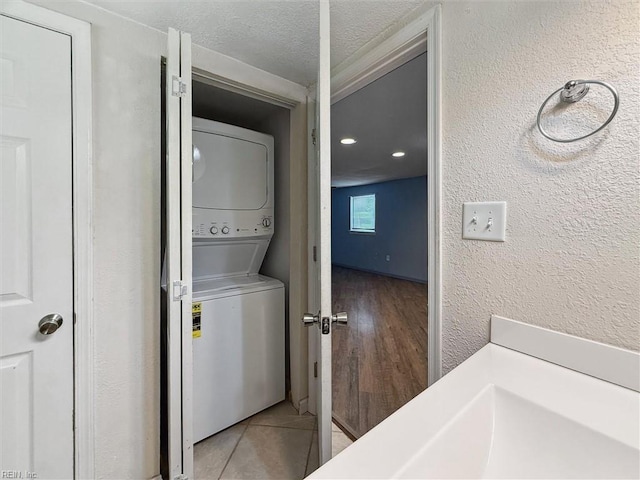 washroom with stacked washing machine and dryer, a textured wall, and a textured ceiling