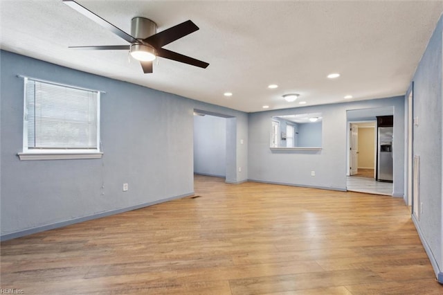 empty room featuring light wood finished floors, ceiling fan, recessed lighting, and baseboards
