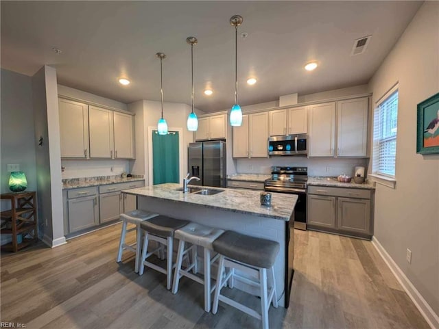 kitchen with stainless steel appliances, gray cabinets, a sink, light wood-style floors, and recessed lighting