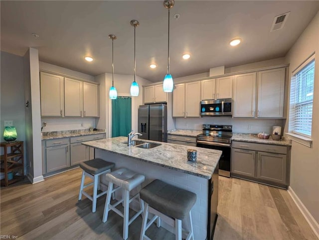 kitchen featuring stainless steel appliances, gray cabinetry, a sink, light wood-type flooring, and recessed lighting