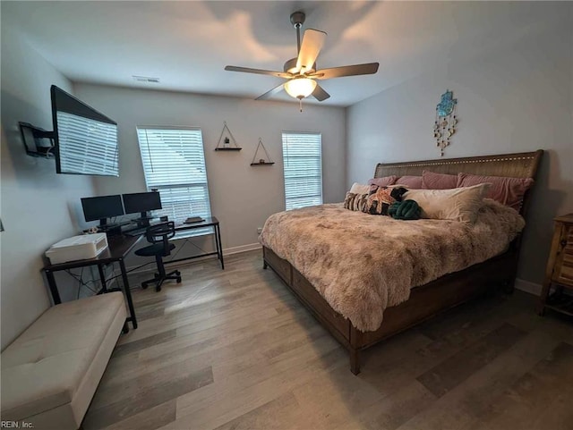 bedroom with a desk, light wood finished floors, baseboards, and ceiling fan