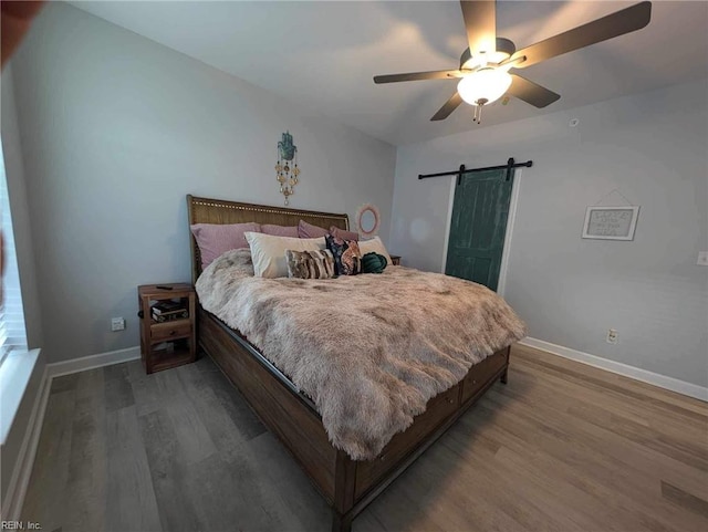 bedroom featuring wood finished floors, baseboards, and a barn door