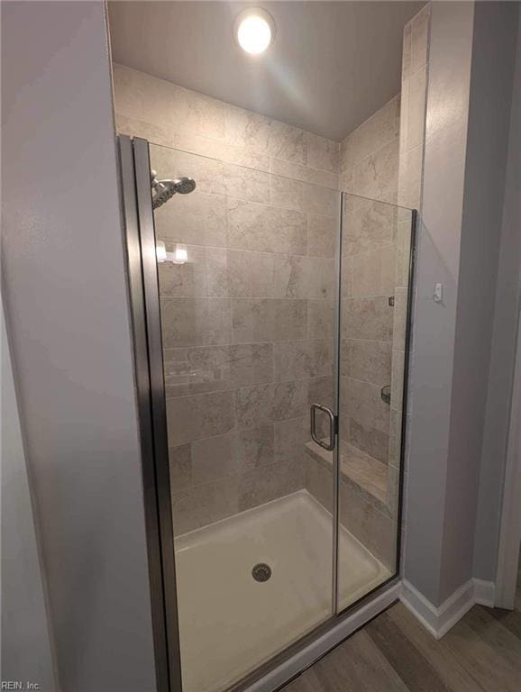 full bath with a shower stall, wood finished floors, and baseboards
