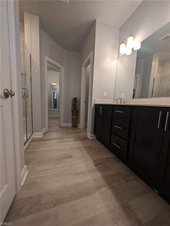 full bathroom with a shower stall, wood finished floors, baseboards, and vanity