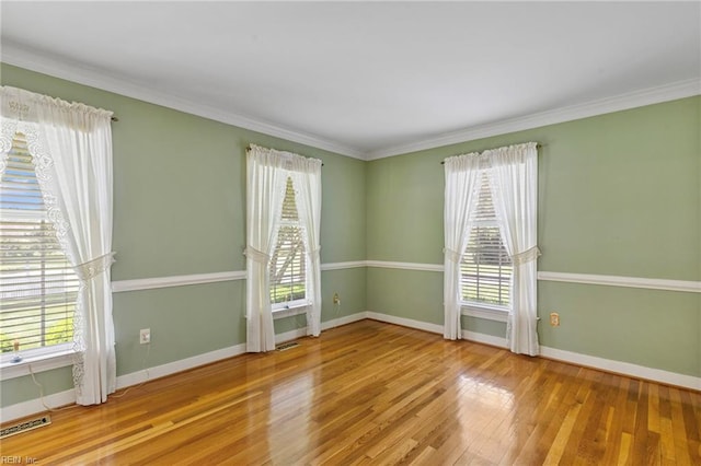 unfurnished room with healthy amount of natural light, baseboards, wood finished floors, and crown molding