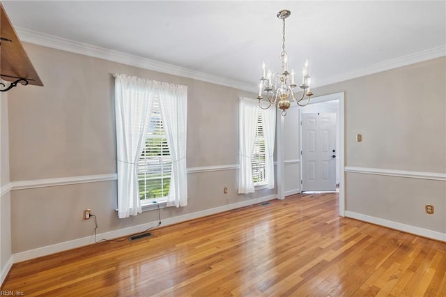 unfurnished dining area with a chandelier, wood finished floors, ornamental molding, and baseboards