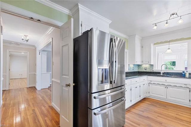 kitchen with stainless steel fridge with ice dispenser, a sink, light wood-style floors, white cabinets, and ornamental molding