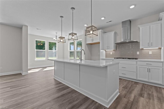 224 Preserve Way, Suffolk, VA 23434 - kitchen featuring wall chimney exhaust hood, light countertops, white cabinets, decorative backsplash, and a kitchen island with sink