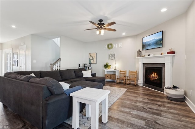 110 Sea Hero Ct, Suffolk, VA 23435 - living room featuring dark wood-style floors, recessed lighting, a ceiling fan, stairs, and a warm lit fireplace