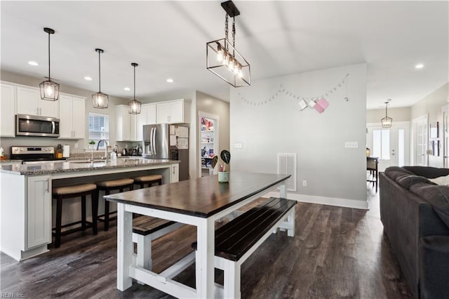 110 Sea Hero Ct, Suffolk, VA 23435 - kitchen featuring stainless steel appliances, light stone countertops, dark wood-style floors, white cabinets, and a kitchen breakfast bar