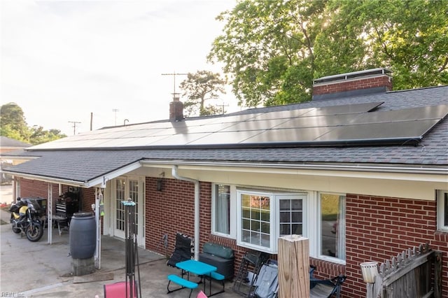 101 Stadium Dr, Chesapeake, VA 23322 - rear view of house with a shingled roof, brick siding, a chimney, a patio area, and solar panels