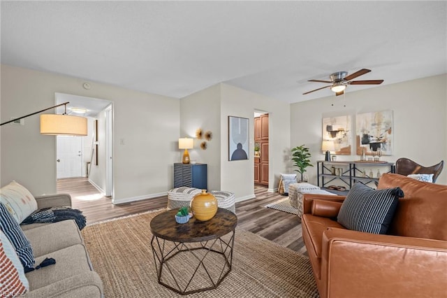 living area with wood finished floors, a ceiling fan, and baseboards
