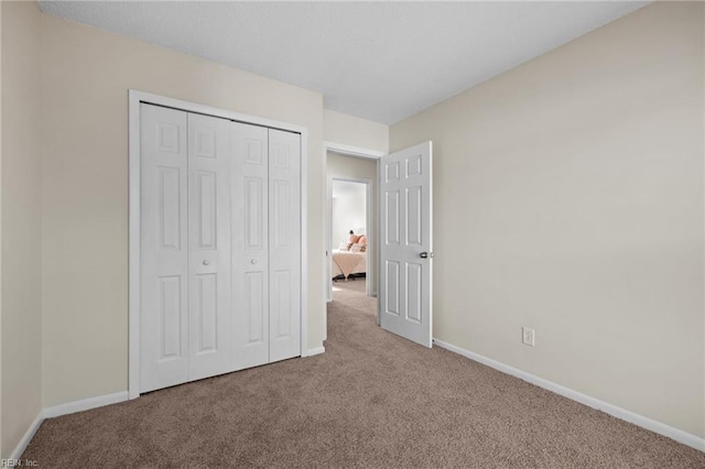 unfurnished bedroom with carpet flooring, baseboards, and a closet