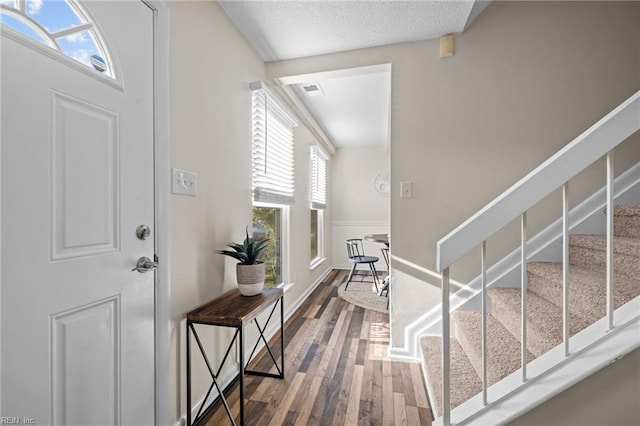foyer featuring wood finished floors, healthy amount of natural light, stairway, and a textured ceiling
