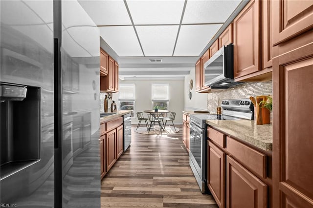 kitchen featuring stainless steel appliances, dark wood-style floors, decorative backsplash, brown cabinets, and a sink