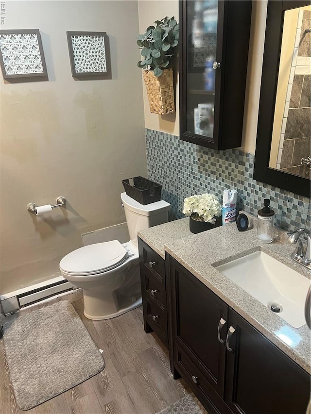 bathroom featuring a baseboard radiator, wood finished floors, toilet, and vanity