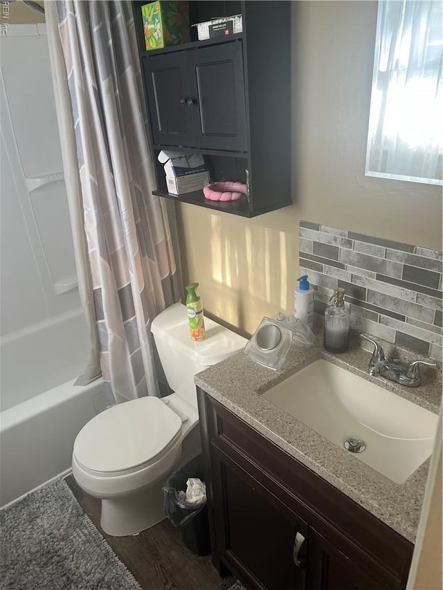 full bath featuring toilet, decorative backsplash, shower / bath combo, and vanity