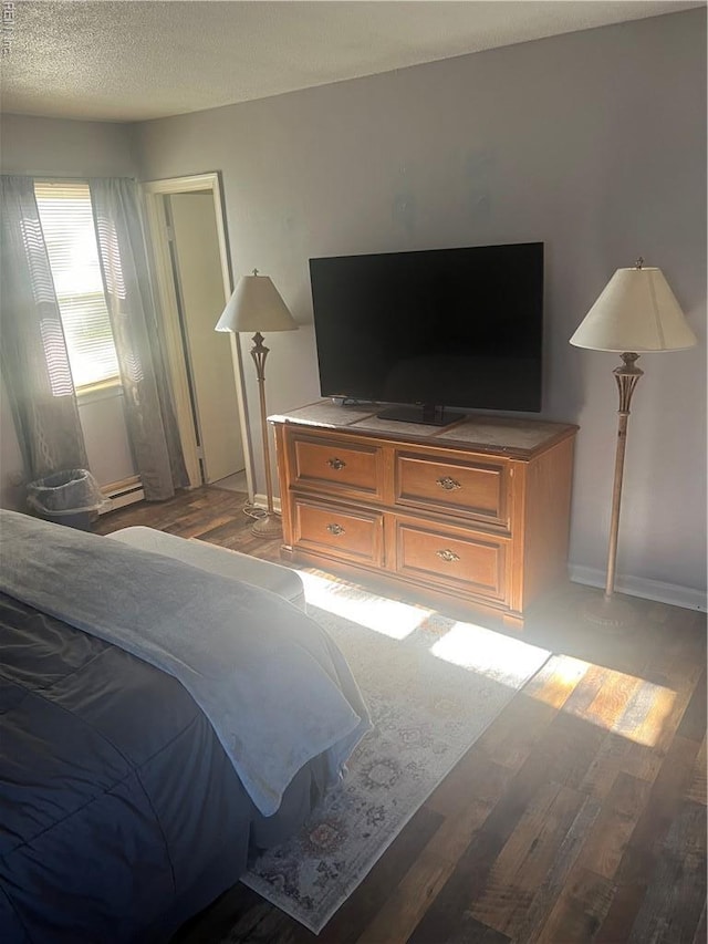 bedroom with light wood-type flooring, baseboard heating, and baseboards