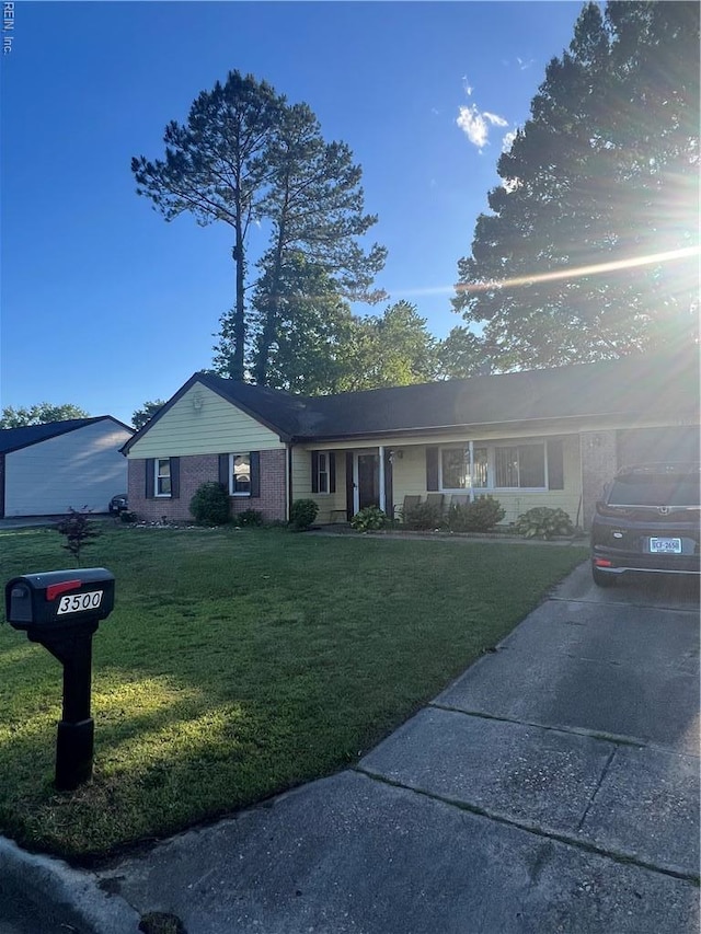 single story home featuring brick siding, a front yard, and driveway