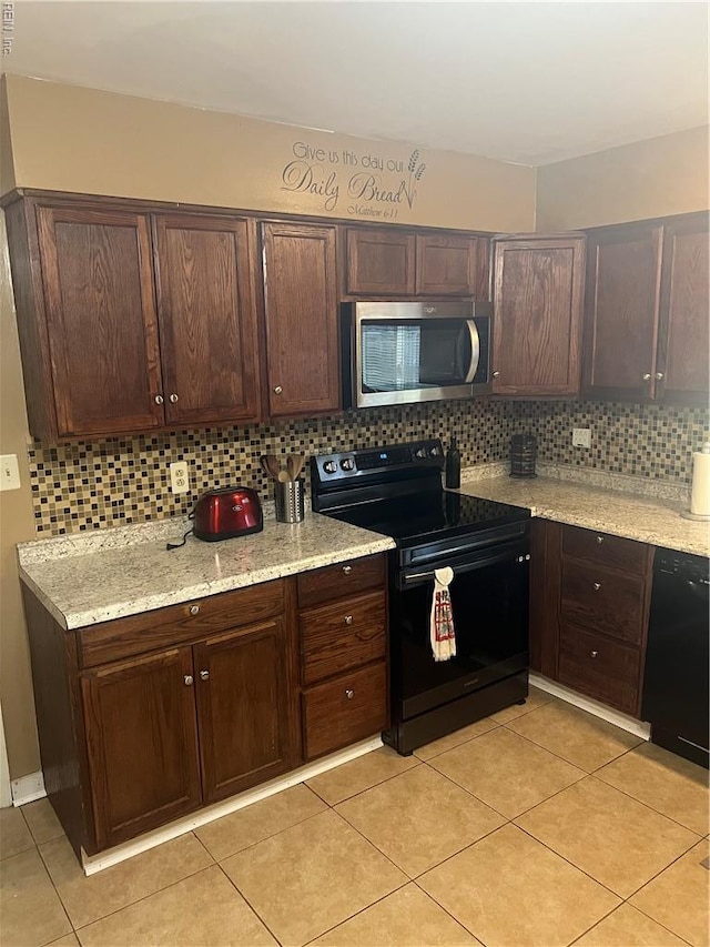kitchen with black appliances, tasteful backsplash, dark brown cabinetry, light tile patterned floors, and light stone countertops