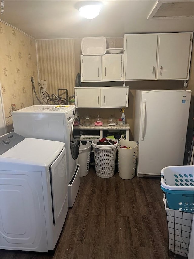 laundry room featuring cabinet space, wallpapered walls, dark wood-style flooring, and separate washer and dryer