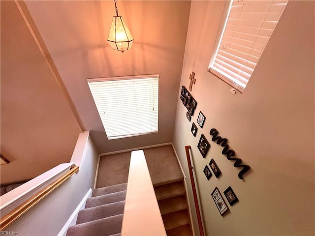 staircase featuring carpet, baseboards, and a towering ceiling