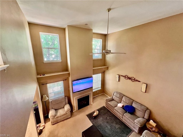carpeted living room with a fireplace and ceiling fan