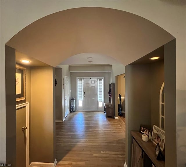 corridor featuring arched walkways, wood finished floors, baseboards, and recessed lighting