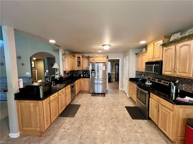 kitchen with stainless steel appliances, a sink, arched walkways, tasteful backsplash, and glass insert cabinets